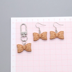 Close-up of resin polka dot bow earrings and keychain with scale measurement view