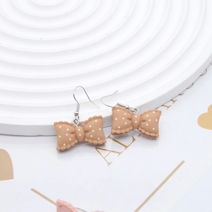 Close-up of pink polka dot resin bow earrings with silver metal hooks on display