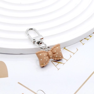 Close-up of cute brown resin bow charm with white polka dots and silver metal clasp