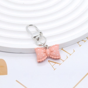 Macro shot of pink polka dot resin bow keychain with silver lobster clasp on white stairs