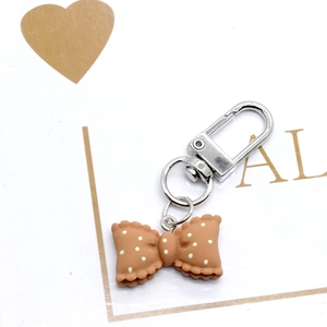 Close-up of brown resin bow keychain with white polka dots and silver metal ring