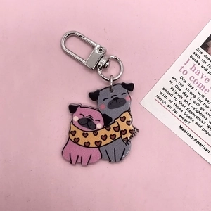 Gros plan du mignon porte-clés carlin en acrylique avec écharpes à cœurs sur rose