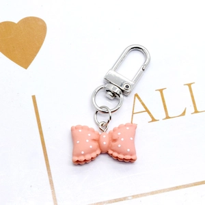 Detailed view of a pink polka dot resin bow keychain with a silver alloy lobster clasp