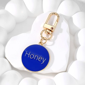Detailaufnahme eines vergoldeten Karabiners und blauem Honey Herz-Schlüsselanhänger