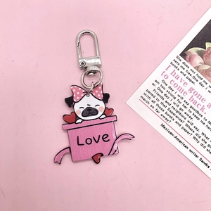 Détail d'un porte-clés carlin en acrylique dans une boîte cadeau Love rose pour sac