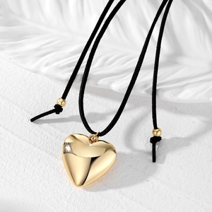 Collier minimaliste avec pendentif cœur doré et cordon ajustable en daim noir sur fond blanc