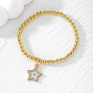 Macro view of gold beaded bracelet featuring a star-shaped evil eye charm and crystal accents