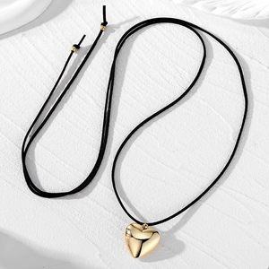 Collier élégant avec pendentif cœur doré et cordon noir sur une surface blanche