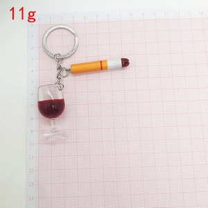 Detail of creative cigarette and wine glass keychain on grid scale background with 11g weight label
