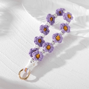 Detailed macro view of handmade purple and yellow crochet daisy charm with gold ring clasp