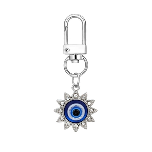 Detailed close-up of a silver sunburst evil eye keychain with blue beads and crystals