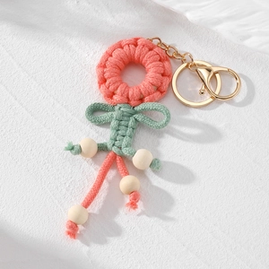 Detail eines handgewebten Blumen-Schlüsselanhängers mit rosa Garn und Holzperlen