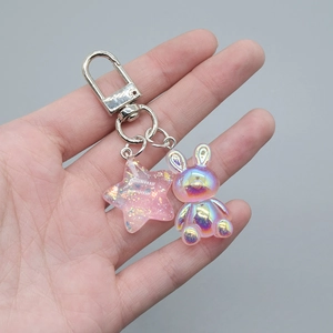 Detail of pink translucent star and pearlized rabbit keychain with silver lobster clasp