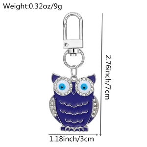 Macro detail of owl charm keychain with blue enamel evil eye and crystal rhinestones