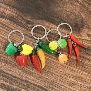 Realistic colorful resin fruit and vegetable keychains on dark wood background