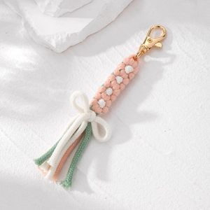 Portachiavi fatto a mano con fiore intrecciato rosa e nappina su sfondo bianco puro
