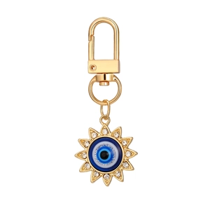 Golden sun-shaped Evil Eye keychain with sparkling crystals and a blue glitter center finish