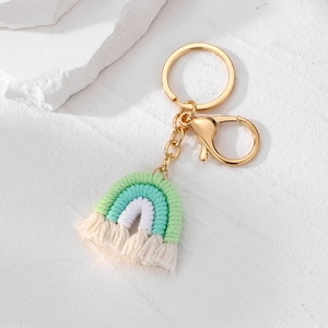 Gros plan du porte-clés arc-en-ciel artisanal avec pompon menthe et fermoir mousqueton doré
