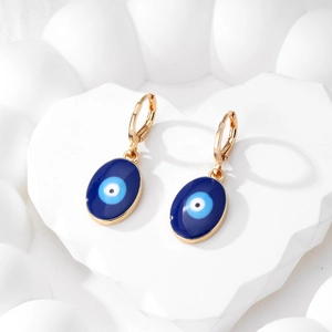 Gros plan détaillé de boucles d'oreilles cœur mauvais œil dorées avec émail bleu