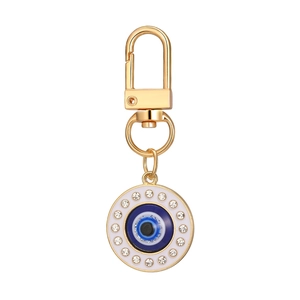 Detail view of a gold-toned evil eye keychain with white enamel and sparkling crystals