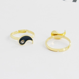 Golden Tai Chi Yin Yang couple rings with black enamel and zircons on white background