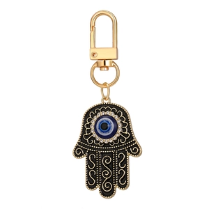 Porte-clés Main de Fatma dorée avec œil bleu et cristaux brillants sur fond blanc