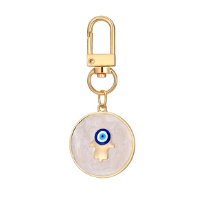 Detailed view of golden Hamsa Hand keychain with blue Evil Eye and marble texture