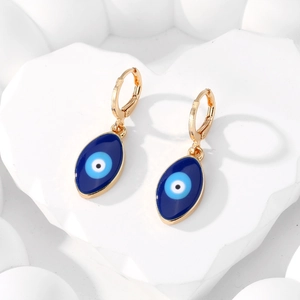 Boucles d'oreilles Evil Eye dorées avec breloques en émail bleu sur support blanc