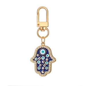 Porte-clés Main de Fatma dorée avec émail bleu, œil protecteur et cristaux