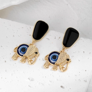 Détail de boucles d'oreilles éléphant dorées avec perles œil bleu sur pierre blanche