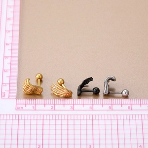 Detalle de pendientes de mano de esqueleto en oro, negro y plata con escala de medición