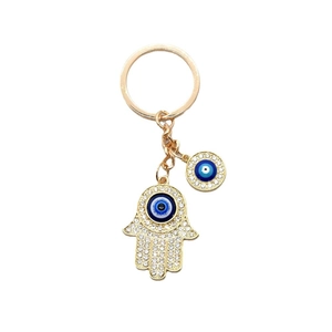 Golden Hamsa Hand and Evil Eye keychain with sparkling crystals on white background
