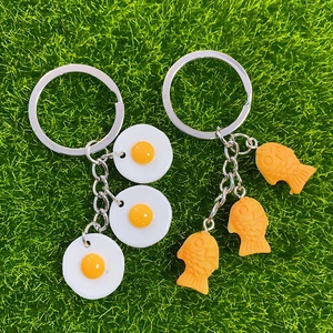 Creative resin food keychains with fried egg and fish cake pendants on green grass