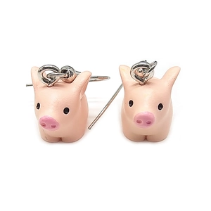 Detalle de pendientes de cerdo rosa hechos de resina con ganchos plateados en fondo blanco