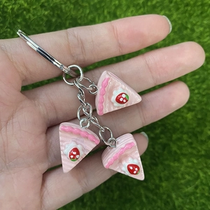 Detail view of mini strawberry layer cake charms with silver metal keychain clips