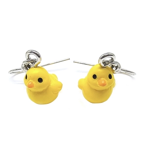 Primer plano de pendientes de pato amarillo hechos de resina con ganchos de metal plateado