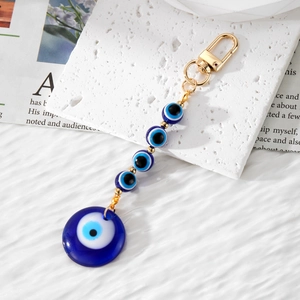 Handmade Evil Eye keychain with blue resin beads and golden lobster clasp on a white background