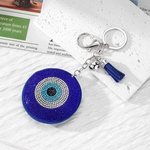 Blue evil eye keychain with sparkling rhinestones and tassels on a decorative background