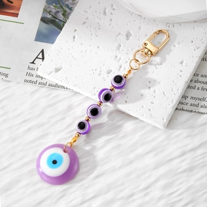 Detail view of purple Evil Eye beaded keychain with golden lobster clasp on marble stone