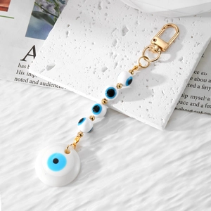 Handmade Evil Eye keychain with blue resin beads and golden clasp on stone board