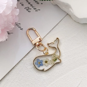 Goldener Delfin-Schlüsselanhänger mit blauen Trockenblumen, eleganter Taschenanhänger