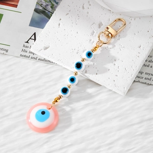 Detail view of pink resin evil eye pendant and beaded chain with golden lobster clasp