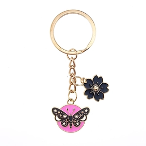 Detailed view of pink butterfly and blue flower charms on a golden metal keychain