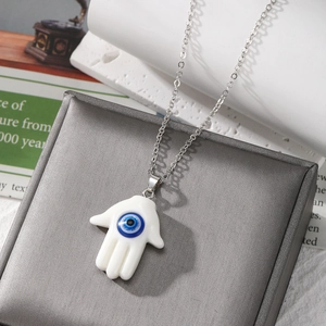 Hamsa Hand necklace with blue Evil Eye pendant on a silver chain displayed on jewelry box