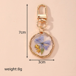Detailed view of handmade resin keychain with blue dried flower and gold fish charm