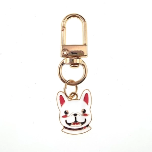 Détail d'un porte-clés bouledogue français en émail blanc avec mousqueton et anneau doré