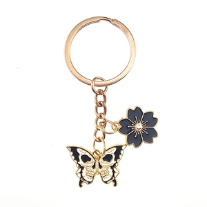 Detail of gothic skeleton butterfly and black cherry blossom charms on gold keychain