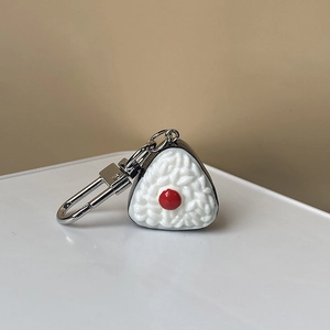 Détail de la texture réaliste des grains de riz et de l'umeboshi rouge sur ce porte-clés sushi