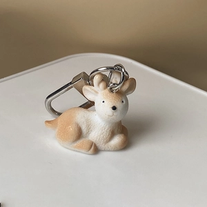Cute cartoon fawn resin keychain with silver metal clip on a minimalist warm background