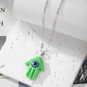 Macro shot of green Hamsa Hand pendant with Evil Eye on a silver chain necklace